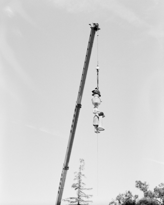 Statue of a woman, lifted midair by a crane